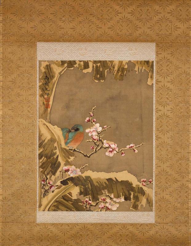 Two birds on a flowering peach branch near a banana plant in snow
