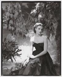 Model Wearing Strapless Dress Seated in Front of Garden Scenery