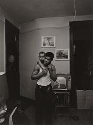 Untitled, [Father (Cox Family) Holding Baby with Donovan, Board of Ed. on TV], from East 100th Street series