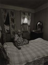 Untitled, [Elderly Woman Sitting on Bed with Clothes in Window], from East 100th Street series