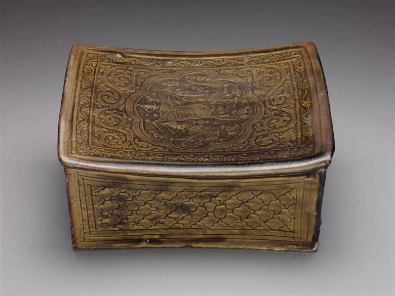 Pillow decorated with dark green glaze over carved and incised ground