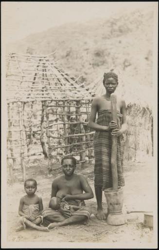 Woman standing with a mortar and pestle, mother sitting and feeding her child, and another child sitting