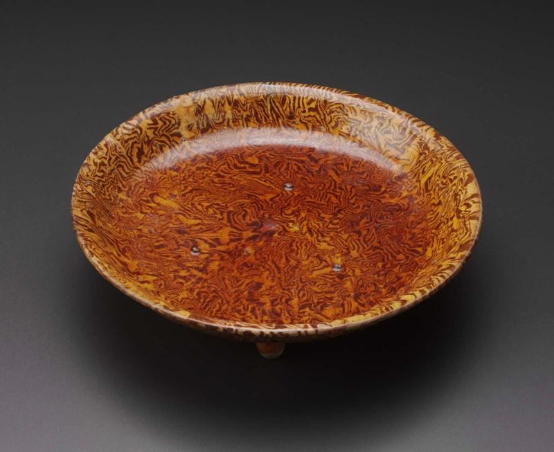 Marbleized plate on three feet decorated with amber glaze