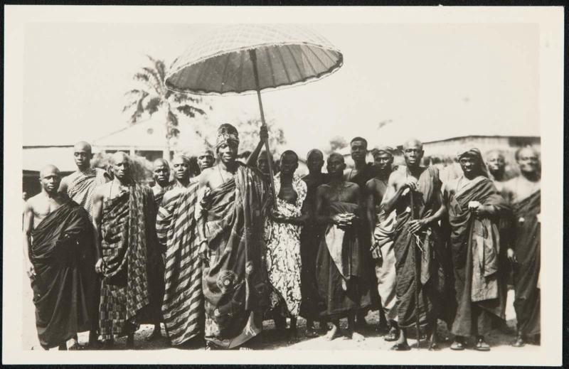 AFRICA - Native African tribal chief with staff of loyal followers. The huge umbrella protects his Majesty's royal head from the African sun.