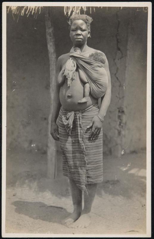 Full-length portrait of a woman with her baby in a sling.