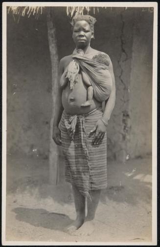Full-length portrait of a woman with her baby in a sling.