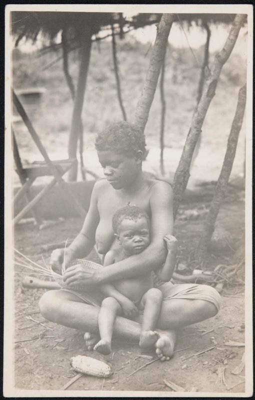 Woman weaving a basket with her baby on her lap.