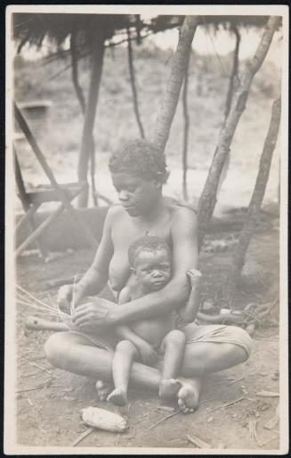 Woman weaving a basket with her baby on her lap.