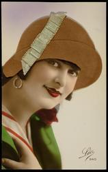 Woman in green coat with brown fabric hat and green ribbon.
