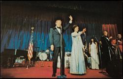 Dinner-jacket clad President Jimmy Carter and wife Rosalynn - she in her famous "old blue formal" - acknowledge applause at one of the Presidential post-inauguration receptions. Carter Inauguration - January 20, 1977.
