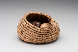 Basket with three doum palm nuts and string inside