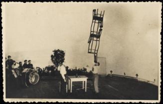 Man balancing chairs on chin