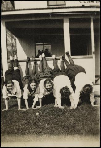 Five women doing handstands on edge of porch