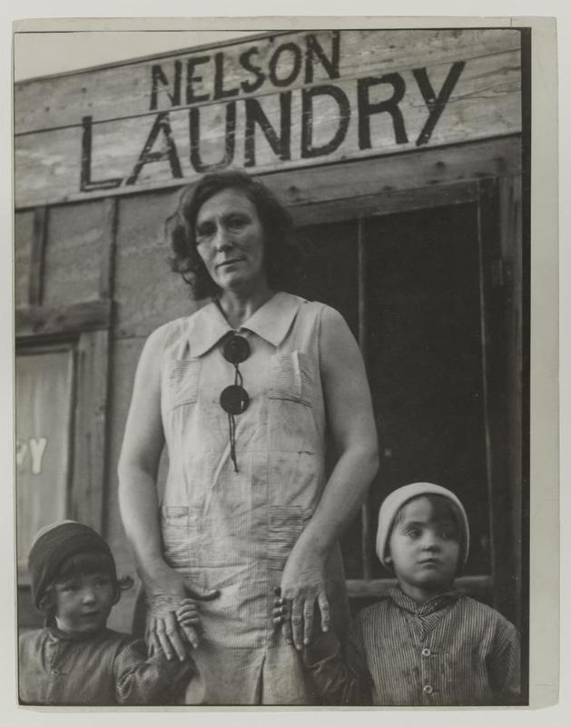 Mrs. Nelson and her two children outside her laundry which she operates without running water