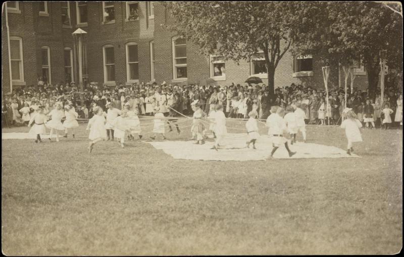 Large group of children around maypole 