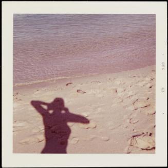 Female shadow at water's edge on otherwise empty beach
