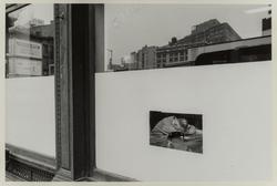 New York City, (view of man with head on desk through window)