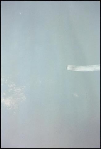 Expanse of blue sky with row of five tiny airplanes and their jetstreams