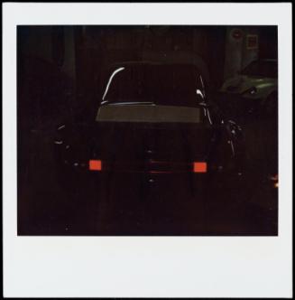 Red tail lights on dark car against dark background