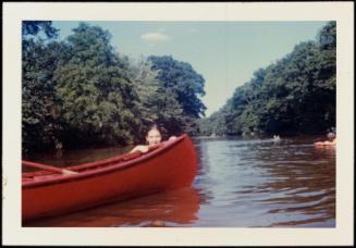 Girl in water holding onto side of red  canoe