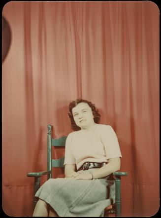 Woman seated in green chair against red backdrop