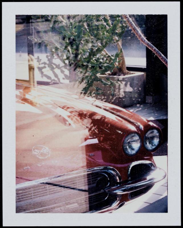 Close-up view through window of hood and headlight of a red Corvette 