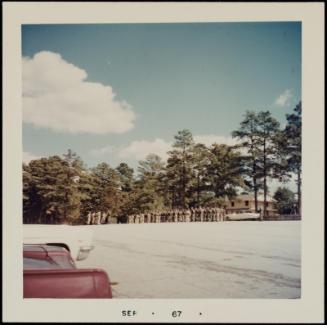 Backs of a red and white car in foreground and group of figures in distance