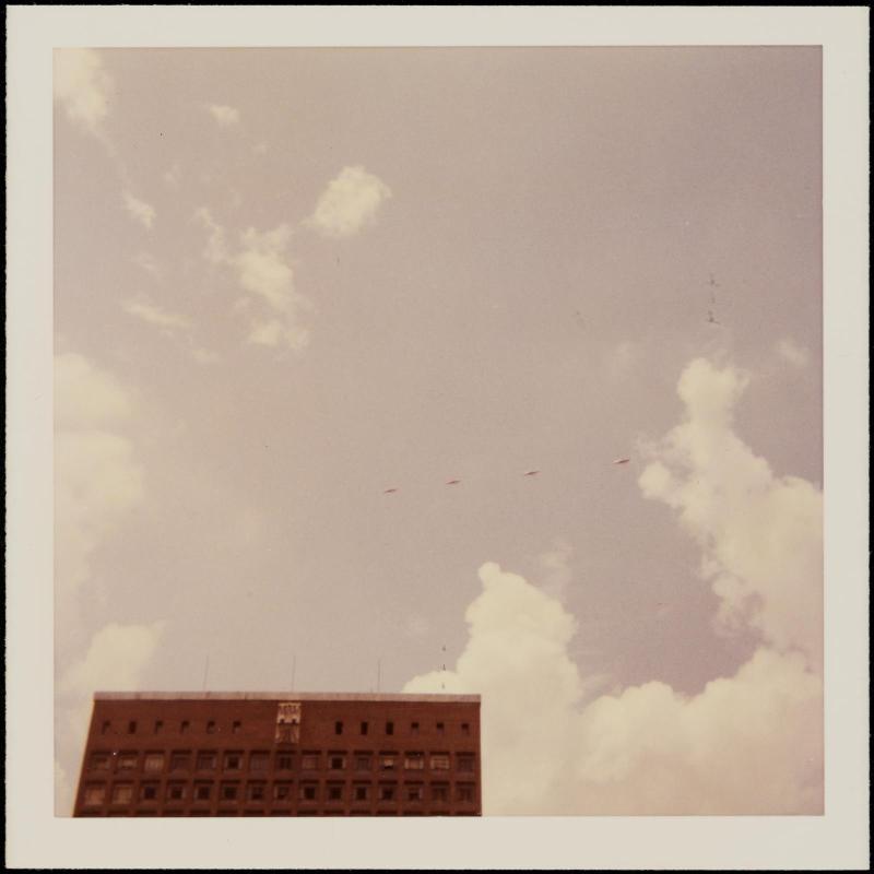 Tiny airplanes visible in sky above red brick building