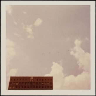 Tiny airplanes visible in sky above red brick building