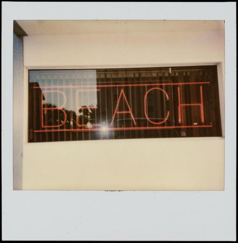 Red neon sign "BEACH" in window