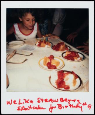 Child blowing out candles in strawberry shortcake