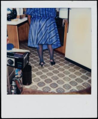 Truncated back view of woman in blue dress in kitchen