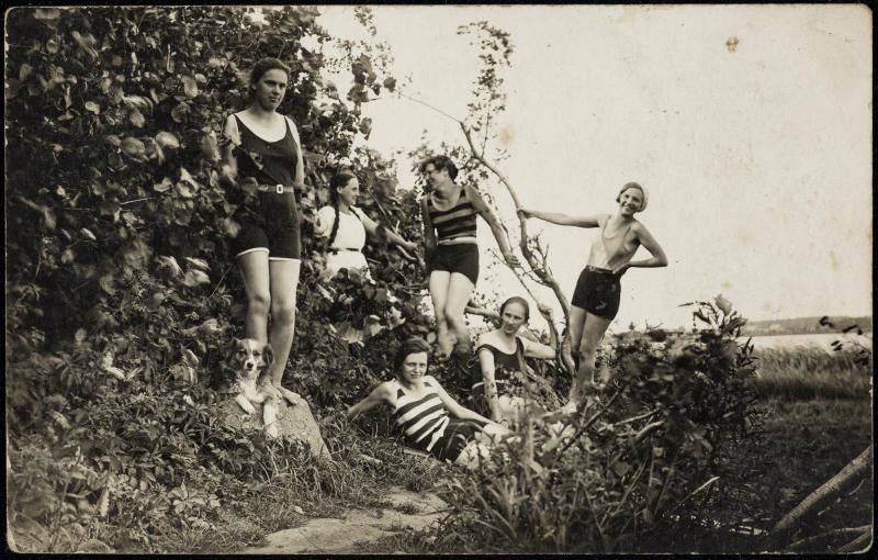 Six women in bathing suits and a dog in the countryside