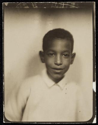 Photo booth portrait of young boy with shy smile and light-colored shirt