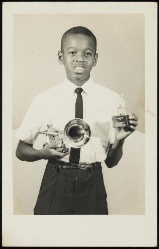 Portrait of young boy holding trumpet and small trophy