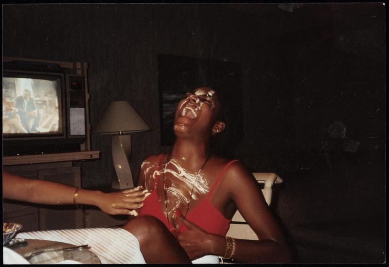 Young woman with head thrown back laughing and being smeared with a white substance