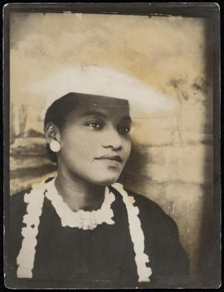 Studio portrait of a woman against a backdrop wearing a hat and round earrings