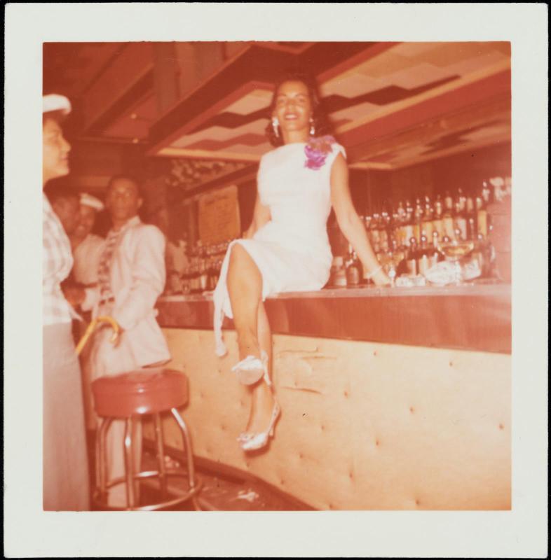 Portrait of woman in white dress and corsage seated on a bar