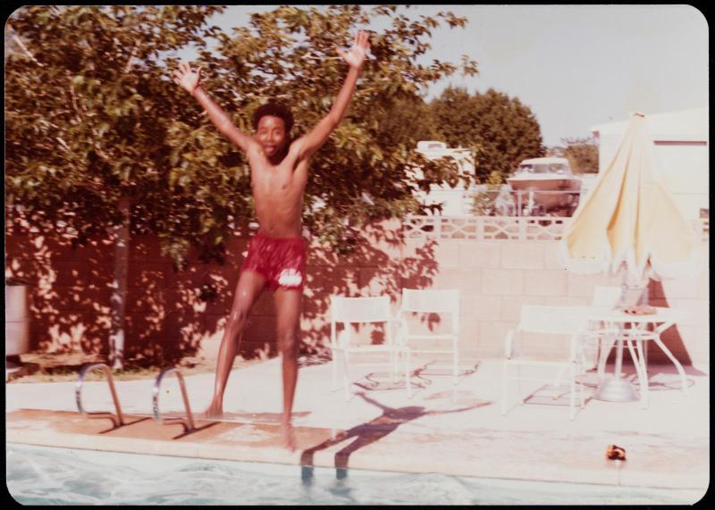 Young man in red swim trunks jumping into swimming pool