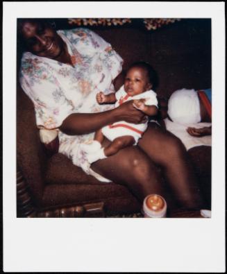 Baby dressed in red and white being held on woman's lap