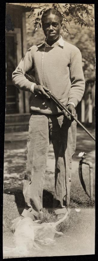 Young man with gun and dead rabbits at his feet