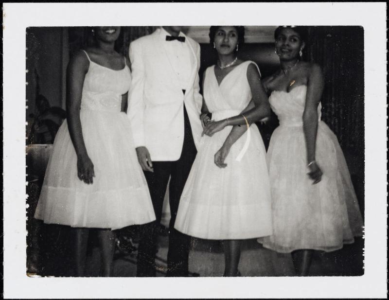 Group of three women and one man in formal attire and heads cropped out of the image