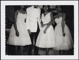 Group of three women and one man in formal attire and heads cropped out of the image