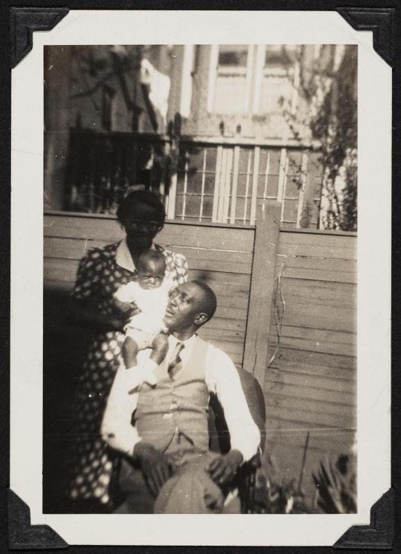 Couple with baby in front of fence