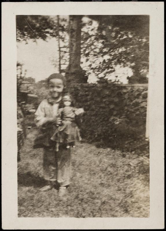 Child posed with doll outdoors
