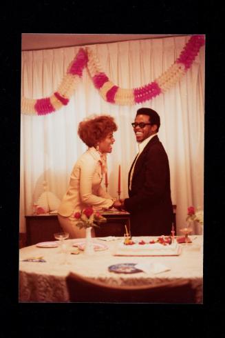 Laughing couple holding hands under a paper garland and next to a table