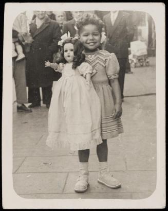 Girl standing and holding white doll