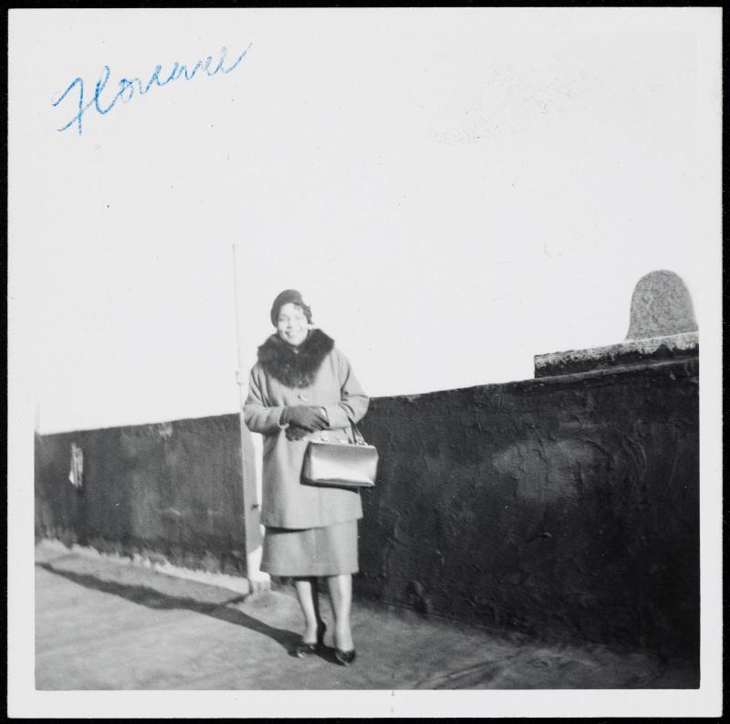 Woman standing on rooftop with fur collar coat and large handbag