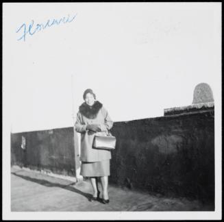 Woman standing on rooftop with fur collar coat and large handbag