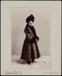 Girl in cloak and hat, standing